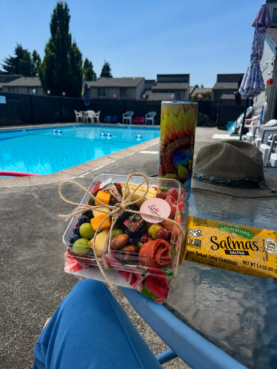 A Cutie Charcuterie to-go box tied with twine, enjoyed poolside